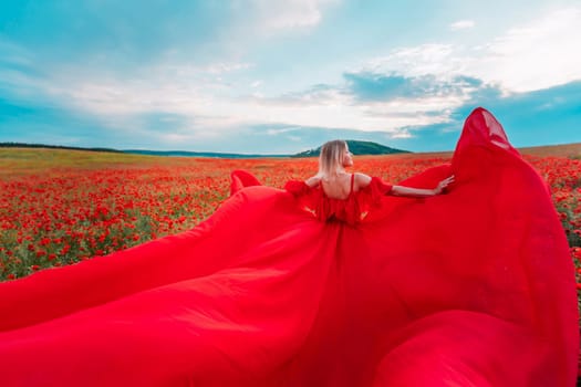 Woman poppy field red dress. Happy woman in a long red dress in a beautiful large poppy field. Blond stands with her back posing on a large field of red poppie