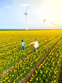 Caucasian Men and Asian women in flower fields seen from above with a drone in the Netherlands, Tulip fields in the Netherlands during Spring, diverse couple in spring flower field