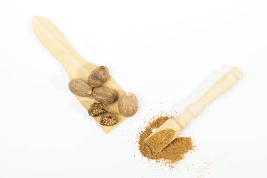 whole nutmeg, halved and ground, on a wooden spoon isolated on a white background and copy space