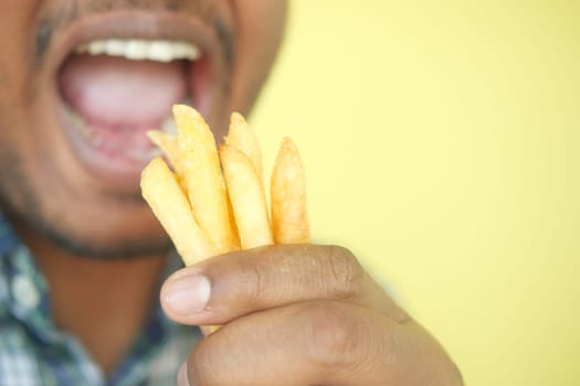 young man eating french fries close up .