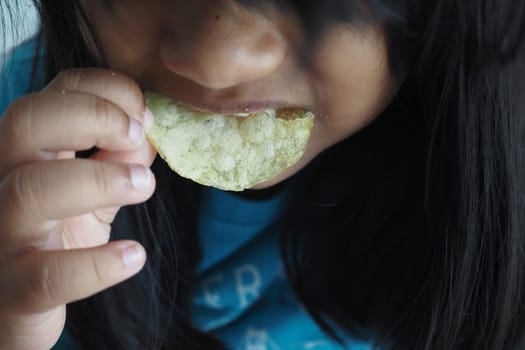 a little girl eating potato chips.