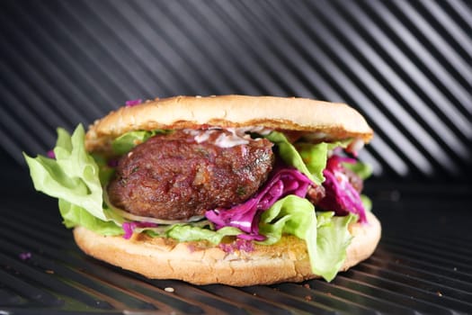 Sandwich with meatballs, lettuce, and red cabbage grilling.