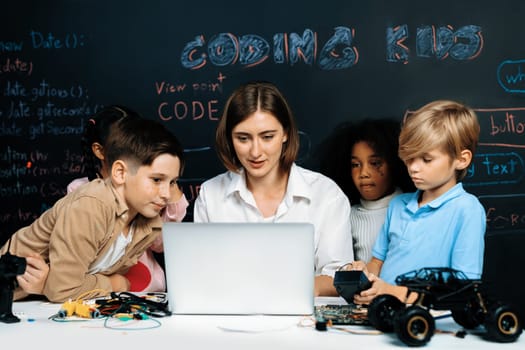 Teacher coding to demonstrate children how to code robots in the STEM class. Children fun to watch how teacher coding with confident only boy in blue shirt taking note with serious look. Erudition.