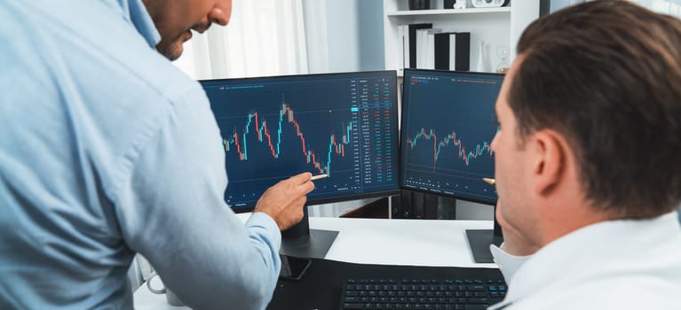 Stock exchange traders discussing digital currency on panorama view in market online focusing on real time dynamic data with two screens, analyzing increased trend investment at workplace. Sellable.