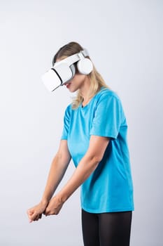 Caucasian girl playing golf and moving gesture by using VR glasses. Happy sport gamer with casual cloth playing game while wearing visual reality headset and standing at pink background. Contraption.