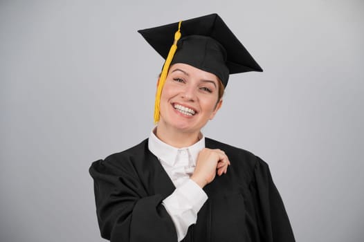 Smiling woman in graduation gown on white background