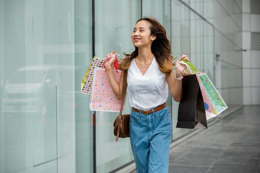 A stylish woman with shopping bags in front of a trendy store window. The perfect shopping day in the city with fashion and consumerism.