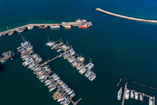 Aerial drone, boats and harbour with ocean, port and marina for travel or cruise holiday. Top view, dock and sea with sailboat, nautical pier or jetty with water scenery and panorama background.
