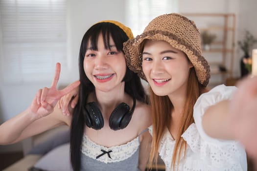 Two women are smiling and posing for a picture. One of them is wearing headphones. Scene is happy and friendly