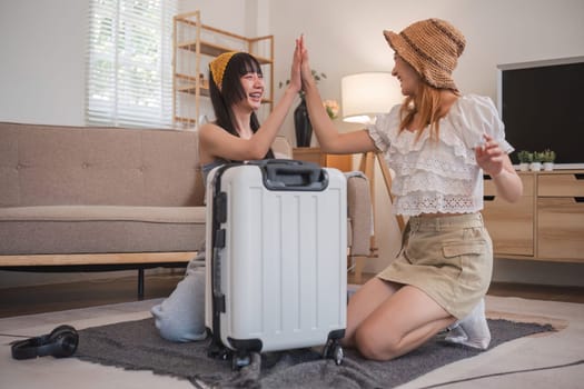 Two women are hugging and one of them is holding a suitcase. Scene is happy and friendly