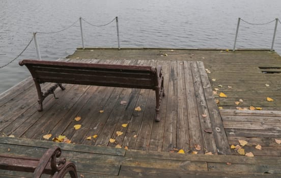 A place to rest on the bank of the river. Wooden pier on the background of the lake, autumn. Place for fishing, rural recreation, camping.