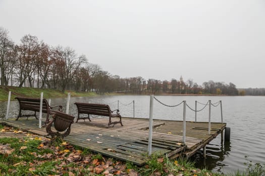 Wooden pier on the background of the lake, autumn. Place for fishing, rural recreation, camping.