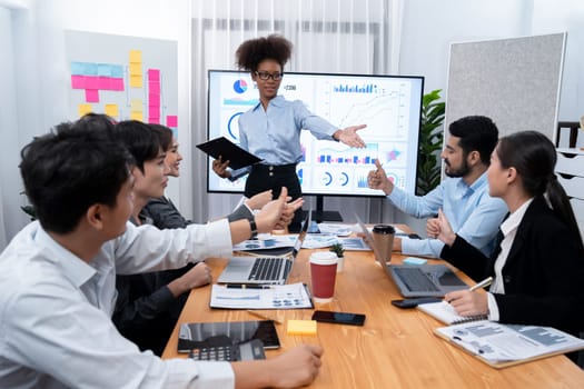 Young african businesswoman presenting data analysis dashboard on TV screen in modern meeting. Business presentation with group of business people in conference room. Concord