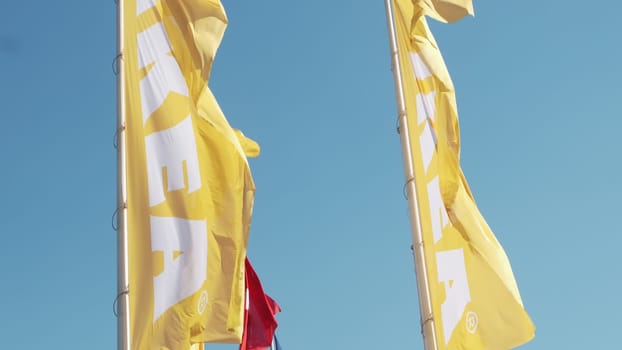 PRAGUE, CZECHIA -APRIL, 2024: Yellow and red IKEA flags waving in the wind against sky.