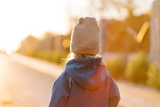 Little girl walks along a sunny road. Back view. High quality photo