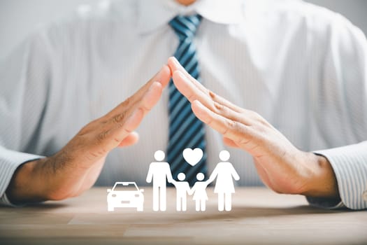 Insuring family well-being and security. Businessman protective gesture with family silhouette. Icons for family, life, health, and house insurance. Reflecting insurance concept.
