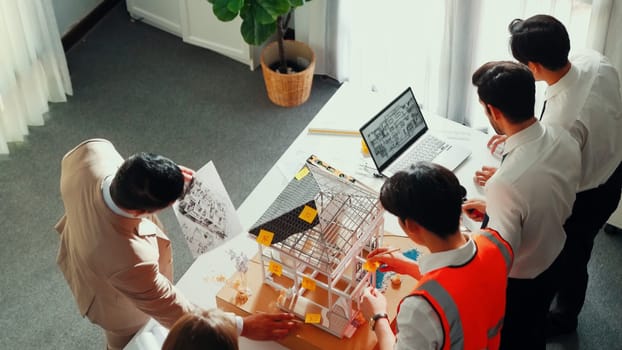 Top view of professional architect engineer team inspect house model while manager holding blueprint and asking about building construction. Group of diverse engineer working together. Alimentation.