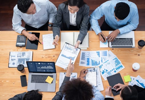 Multiracial analyst team use BI Fintech software to analyze financial data on meeting. Top view finance dashboard data display on laptop screen with analyzed chart for marketing indication. Concord