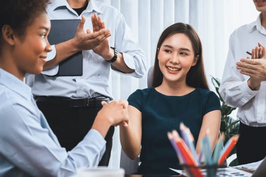 Diverse coworkers celebrate success with handshake and teamwork in corporate workplace. Multicultural team of happy professionals united in solidarity by handshaking in office. Concord