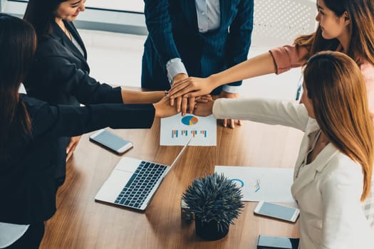 Businesswomen joining hands in group meeting at modern office room showing teamwork, support and unity in work and business. Female power and femininity concept. uds