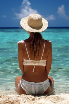 A woman in a white bikini sitting on the beach