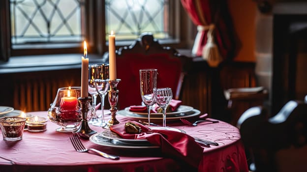 Festive table setting with cutlery, candles and beautiful red flowers in a vase.