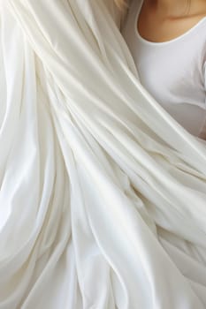 A woman in a white shirt wrapped up under some sheets