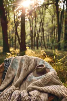 A blanket with a hat on top of it sitting in the woods