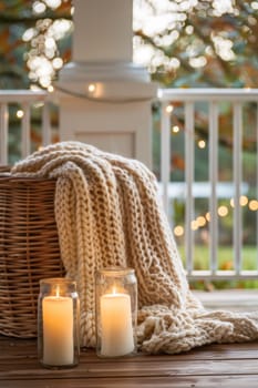 Two candles sit on a blanket next to some yarn