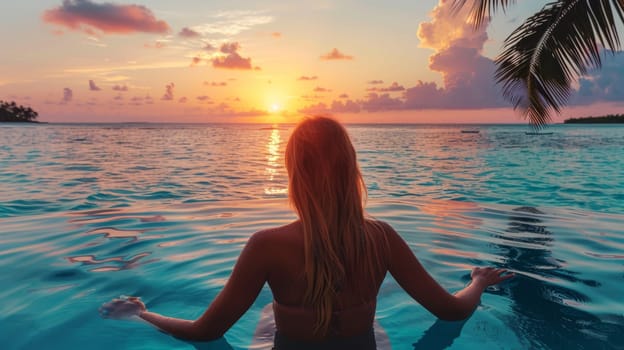 A woman sitting in a pool at sunset with her legs crossed