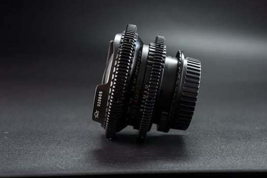 Antique camera lens, showcasing detailed focus rings and scale markings, critical tools for vintage photography, presented on a dark textured surface