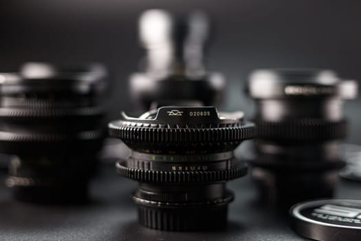 Vintage lens collection in soft focus, one lens with clear serial number stands out, photographic gear ensemble, artistic blur, dark atmospheric lighting
