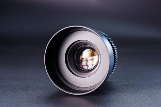 Close-up view of vintage Helios camera lens, black finish, photography gear on dark background, detailed focus rings visible, professional photographic equipment.