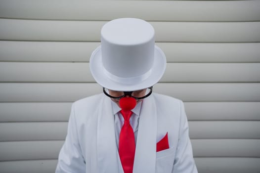 Portrait of a clown in a white classic suit and a vintage high hat