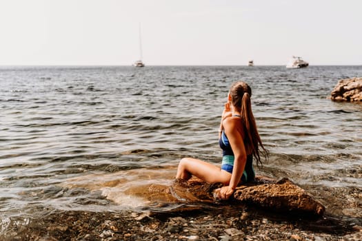 Woman beach vacation photo. A happy tourist in a blue bikini enjoying the scenic view of the sea and volcanic mountains while taking pictures to capture the memories of her travel adventure