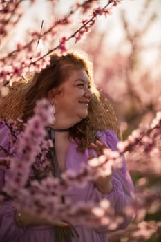 Woman blooming peach orchard. Against the backdrop of a picturesque peach orchard, a woman in a long pink dress and hat enjoys a peaceful walk in the park, surrounded by the beauty of nature