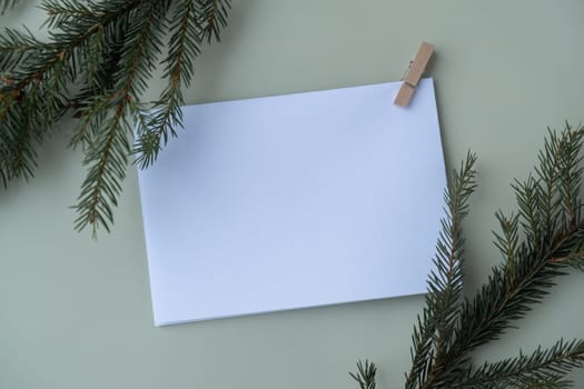 Green background with Christmas tree branch decor and copy space mock up white envelope. Template for Christmas greeting card New Year postcard. Flat lay top view