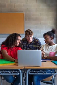 Multiracial group of high school students doing homework research together using laptop in class. Vertical image. Education and technology concept.