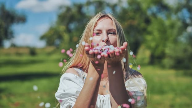 A girl blows a multi-coloured paper confetti out of her hands