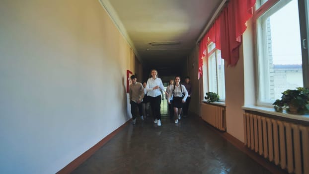 A down-syndrome school boy with group of children in corridor, running.