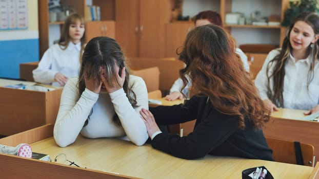 A high school girl cries and her friends comfort her