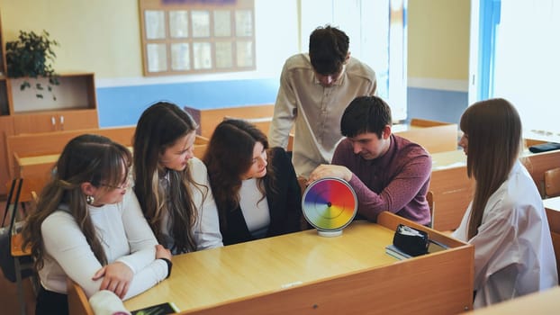 Students in physics class spin Newton's multicolored disk