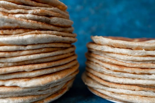 Flatbread lavash, chapati, naan, heap of tortilla on a blue background Homemade flatbread stacked