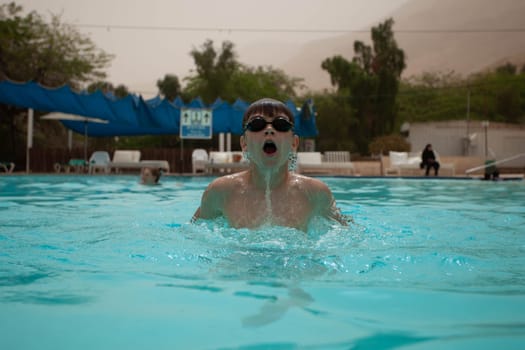 Boy with glasses swims in the pool. High quality photo