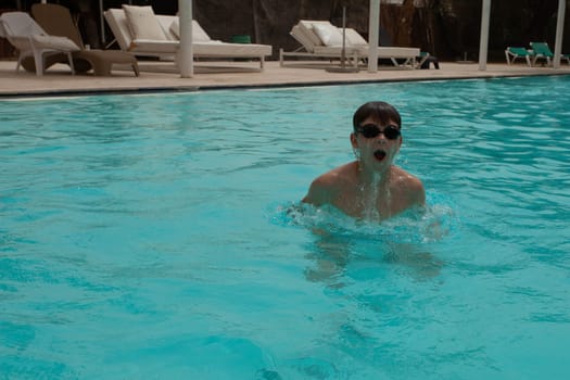 Boy with glasses swims in the pool. High quality photo