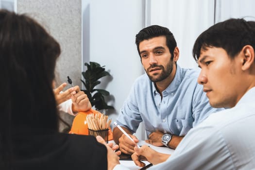 Diverse group of civil engineer and client working together on architectural project, reviewing construction plan and building blueprint at meeting table. Prudent