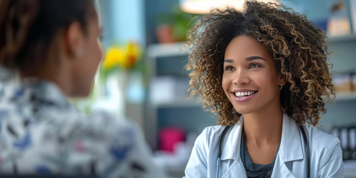 The female doctor is sharing a smile with her patient, her Jheri curl glistening in the electric blue light. Their conversation is fun and happy as they discuss travel plans for an upcoming event