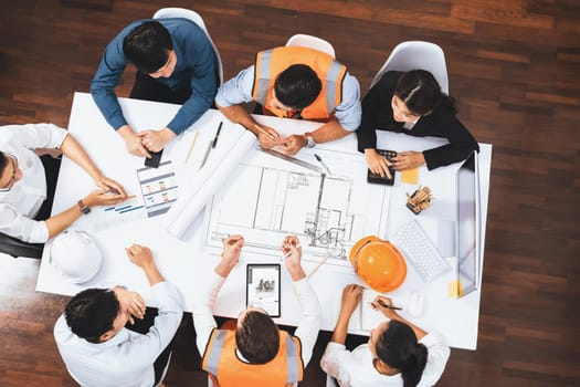 Top view banner of diverse group of civil engineer and client working together on architectural project, reviewing construction plan and building blueprint at meeting table. Prudent