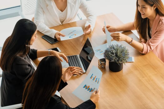 Businesswoman in group meeting discussion with other businesswomen colleagues in modern workplace office with laptop computer and documents on table. People corporate business work team concept. uds