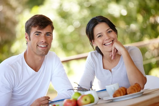 Couple, breakfast and outdoors portrait for eating, love and affection in marriage or romance in nature. People, nutrition and smile at home for healthy relationship, food and relax on vacation.
